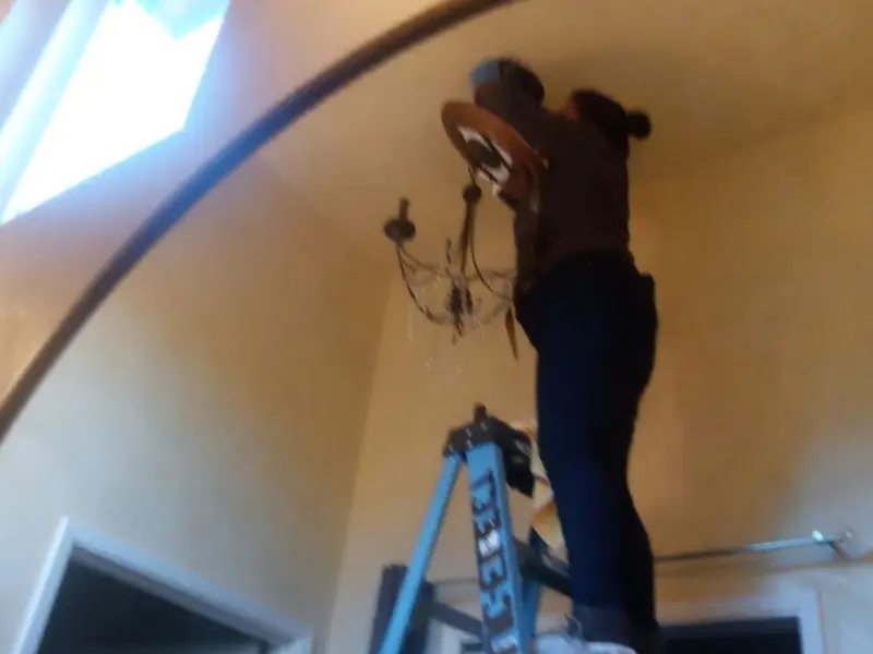 Electrician installing a chandelier in a Mason residence